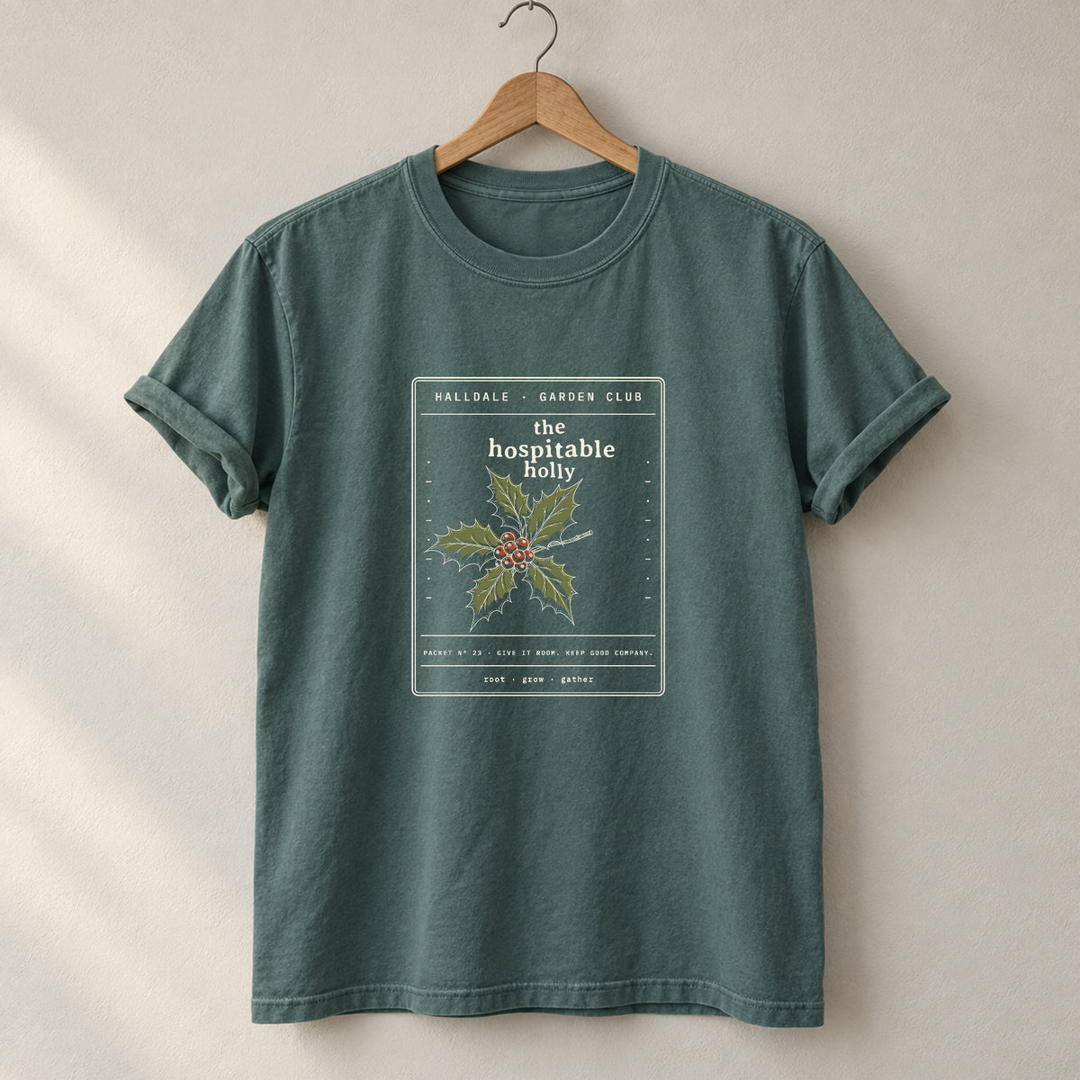 The Hospitable Holly tee in Blue Spruce, on a hanger