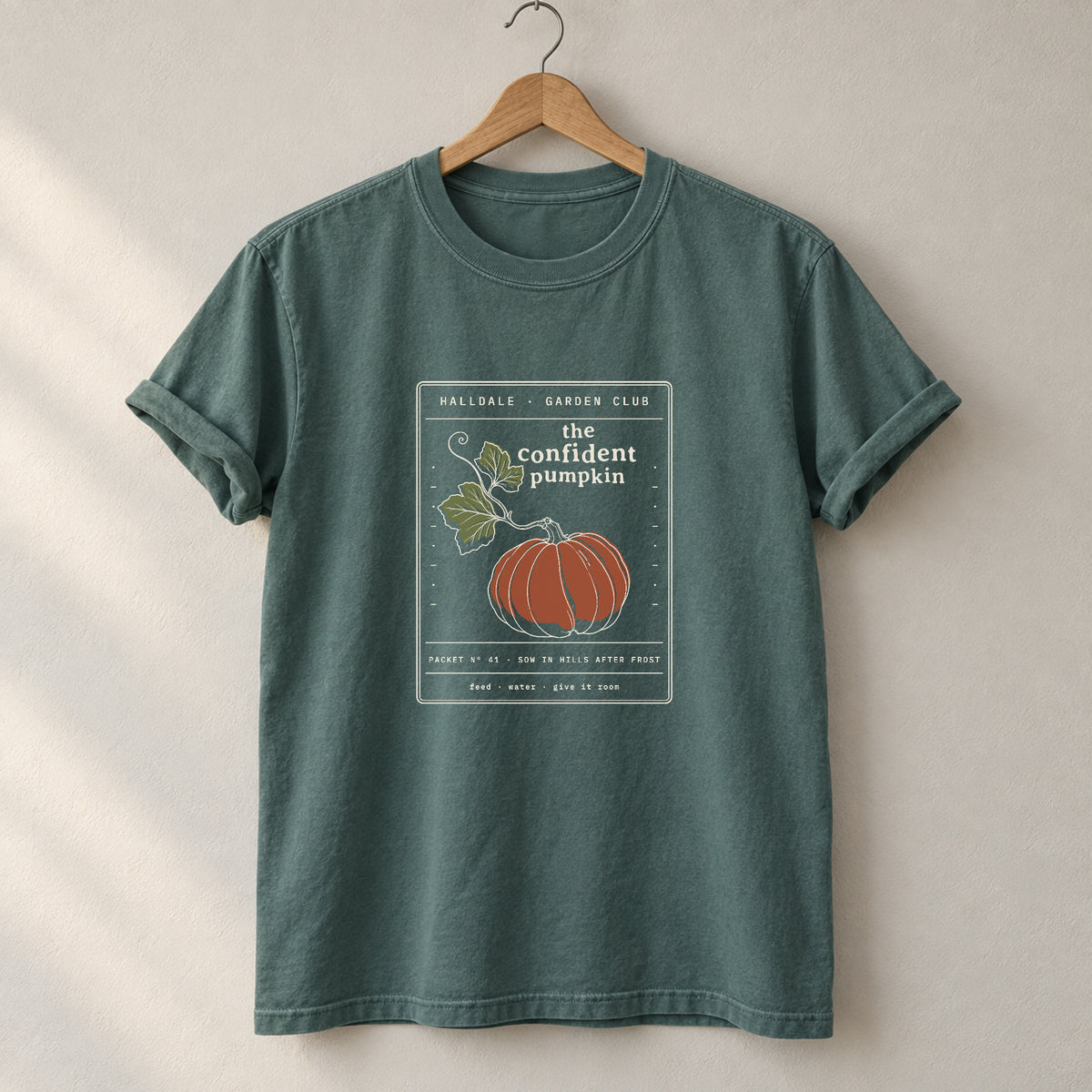 The Confident Pumpkin tee in Blue Spruce, on a hanger