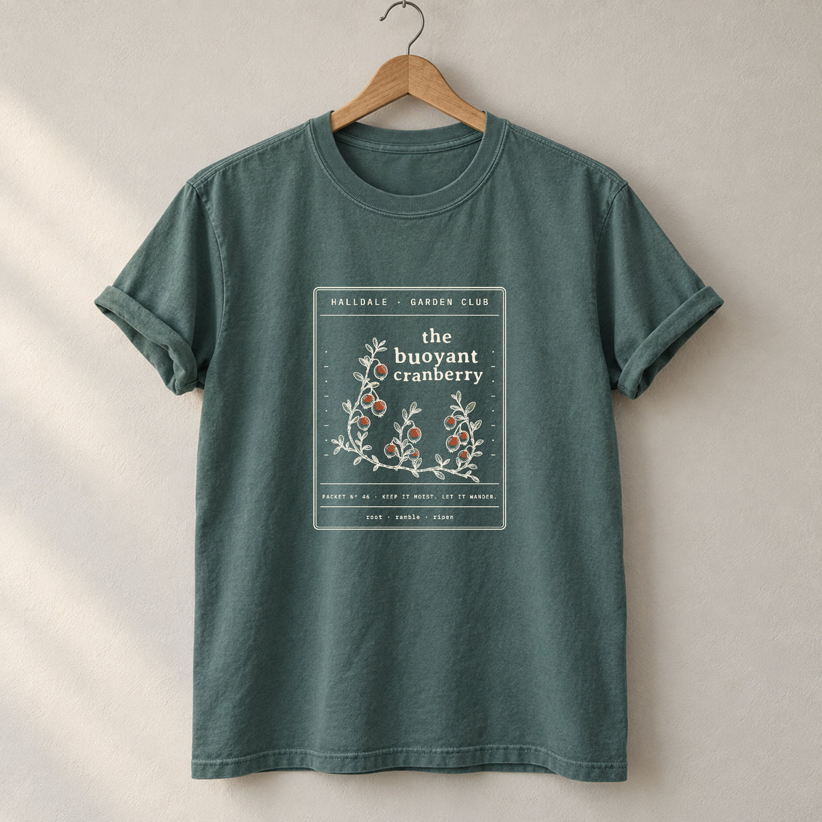 The Buoyant Cranberry tee in Blue Spruce, on a hanger