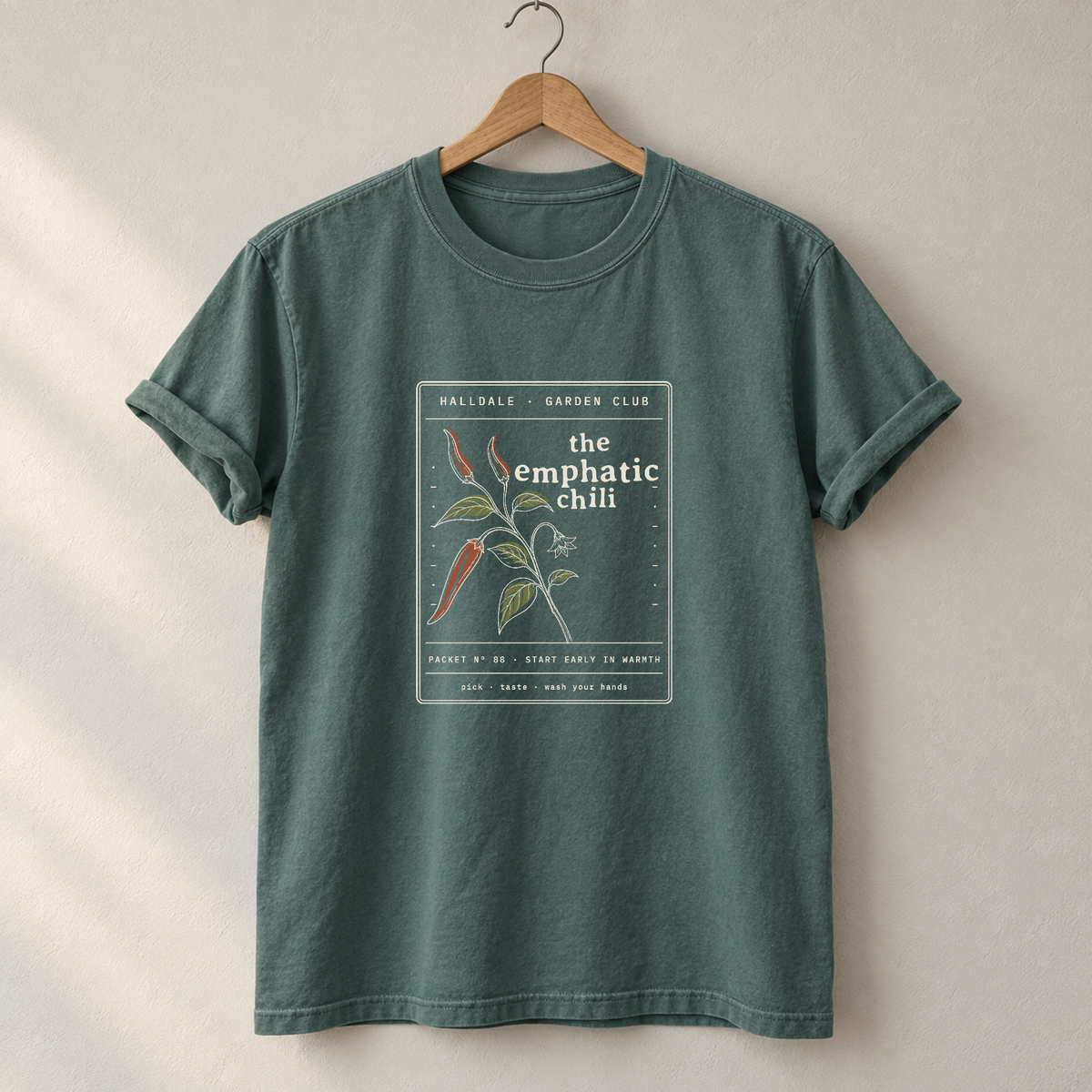 The Emphatic Chili tee in Blue Spruce, on a hanger