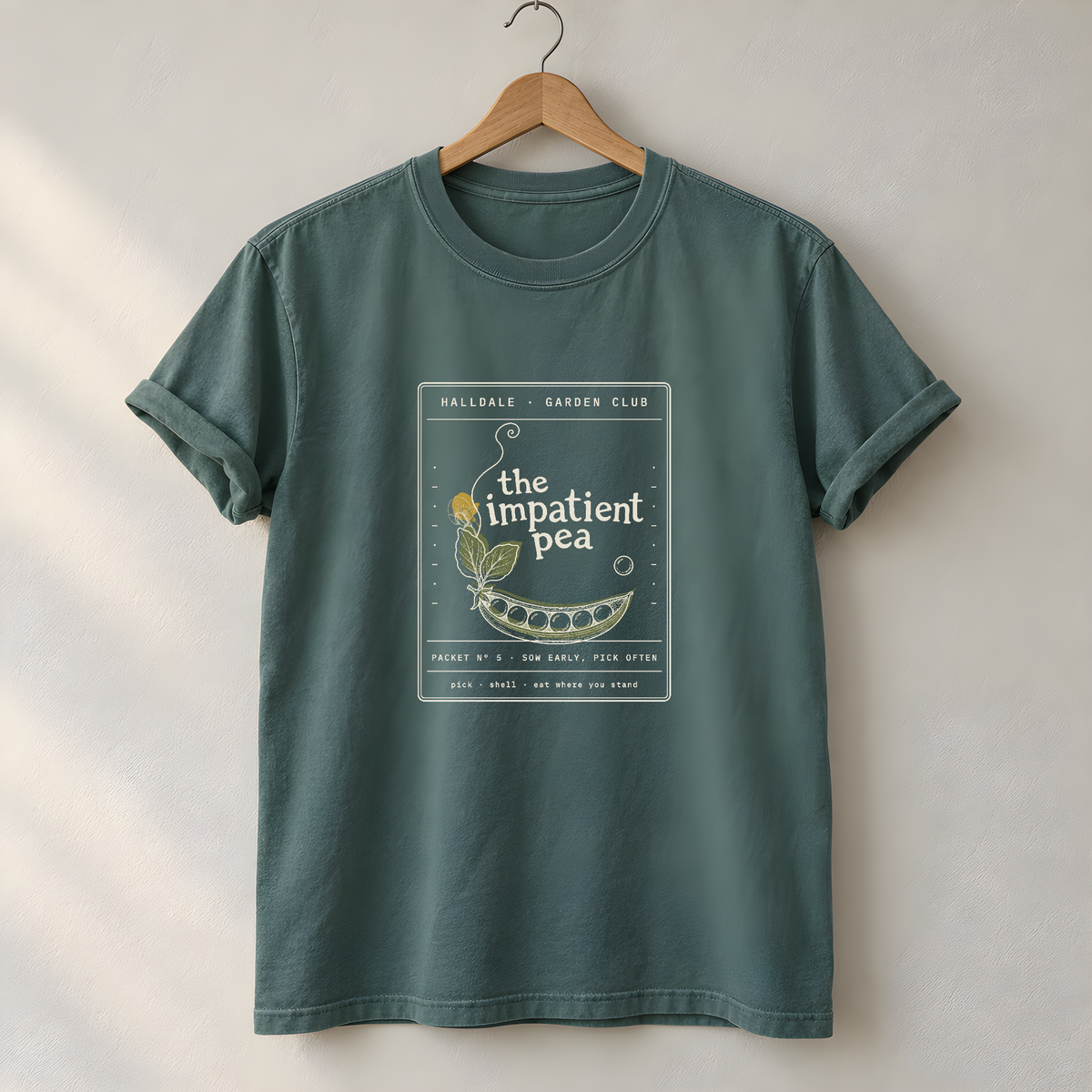 The Impatient Pea tee in Blue Spruce, on a hanger