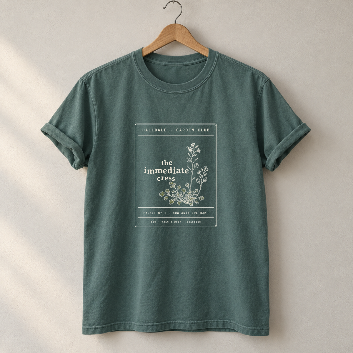 The Immediate Cress tee in Blue Spruce, on a hanger