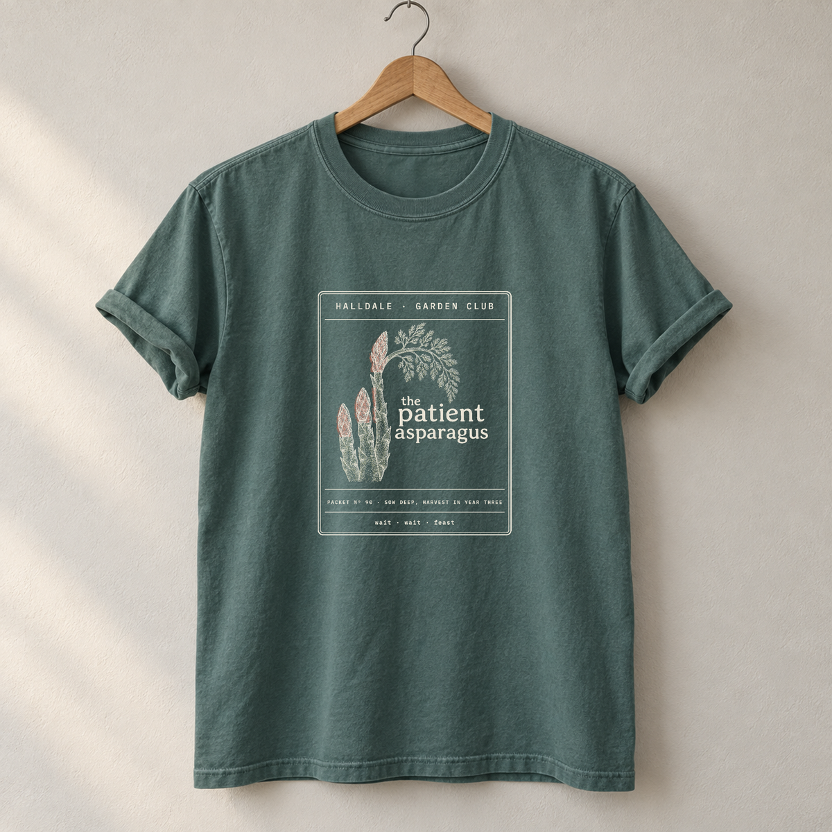The Patient Asparagus tee in Blue Spruce, on a hanger