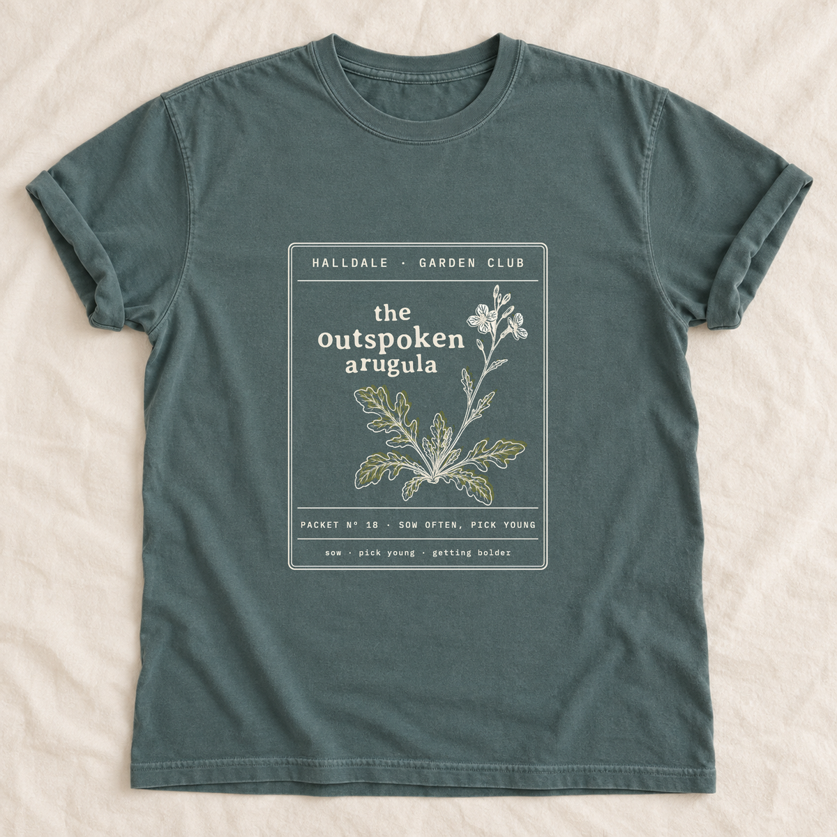 The Outspoken Arugula tee in Blue Spruce, laid flat