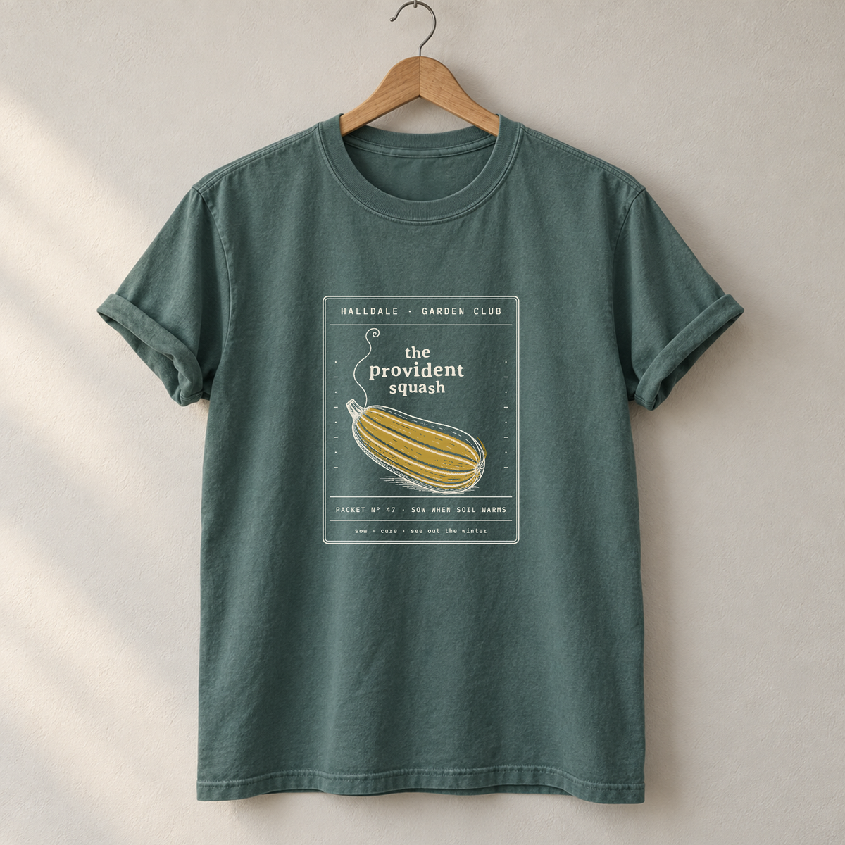 The Provident Squash tee in Blue Spruce, on a hanger