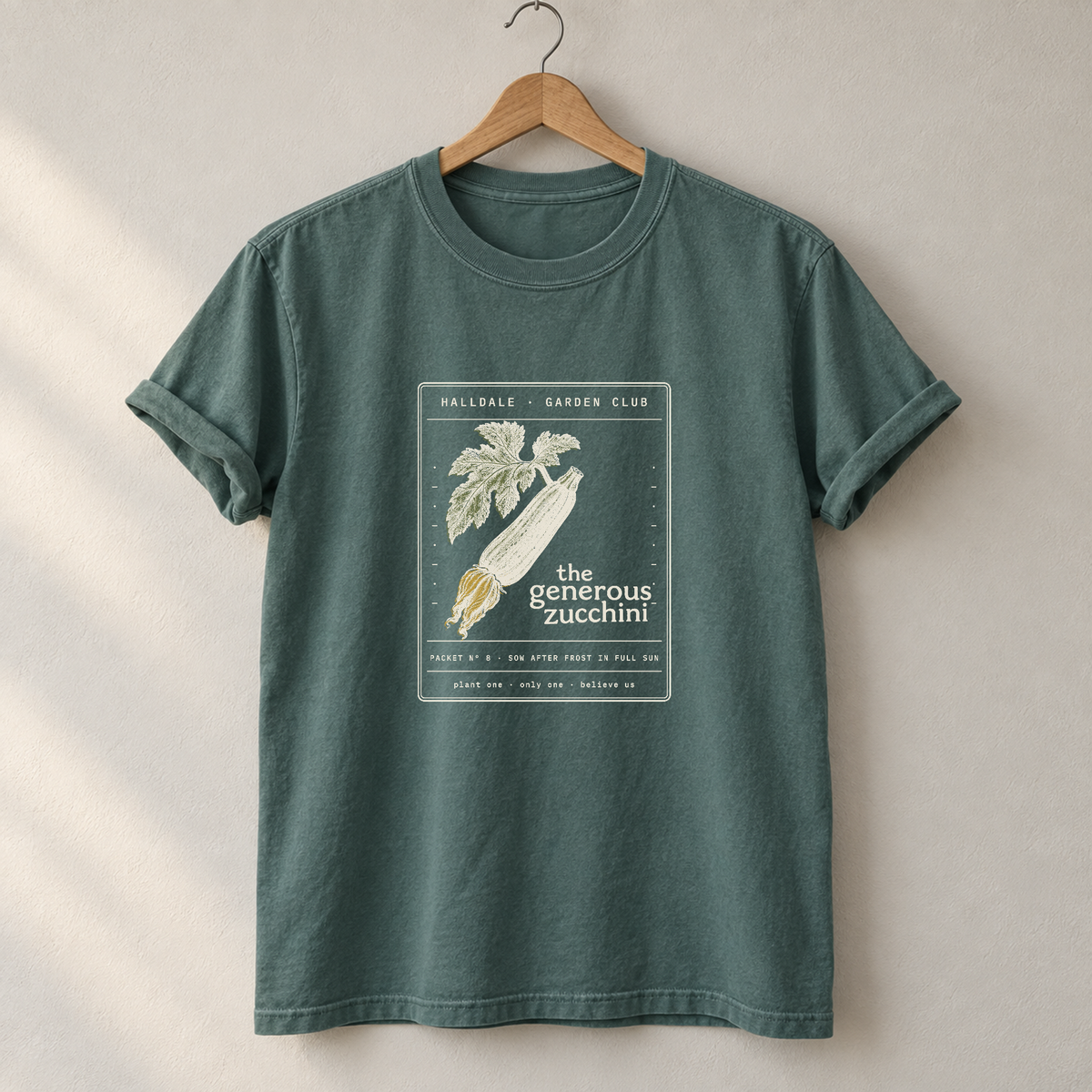 The Generous Zucchini tee in Blue Spruce, on a hanger