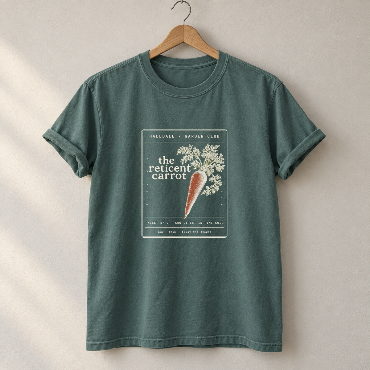The Reticent Carrot tee in Blue Spruce, on a hanger