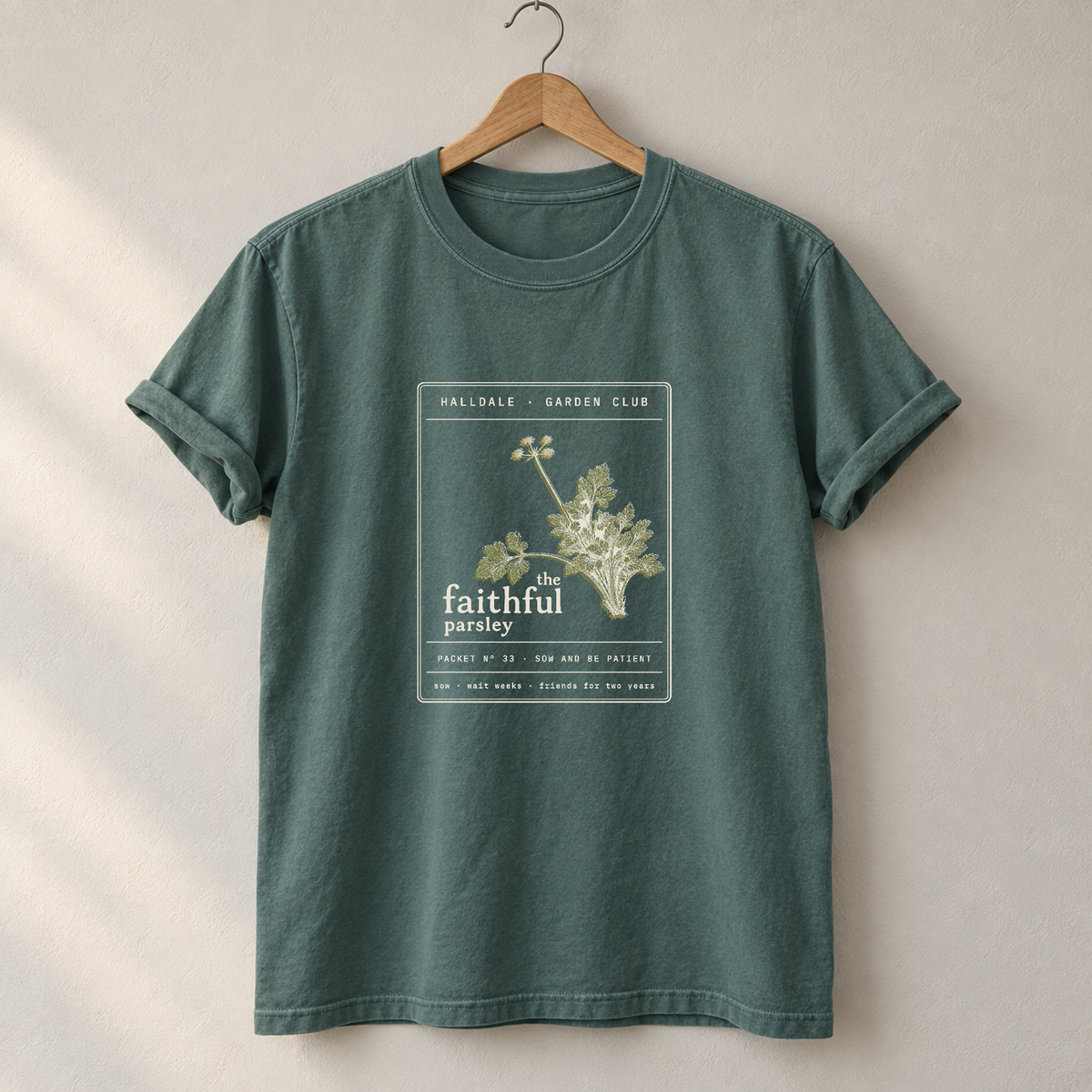 The Faithful Parsley tee in Blue Spruce, on a hanger