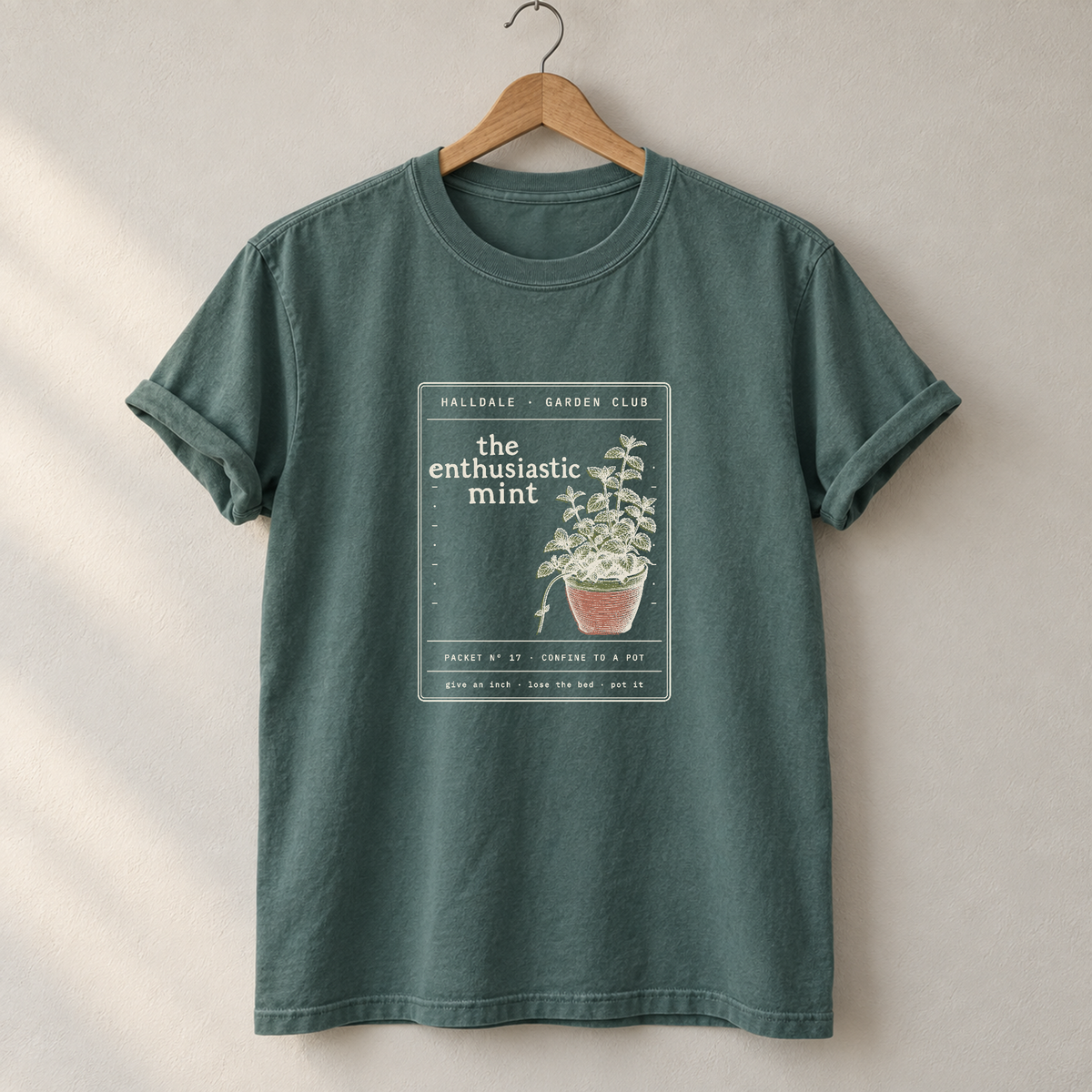 The Enthusiastic Mint tee in Blue Spruce, on a hanger