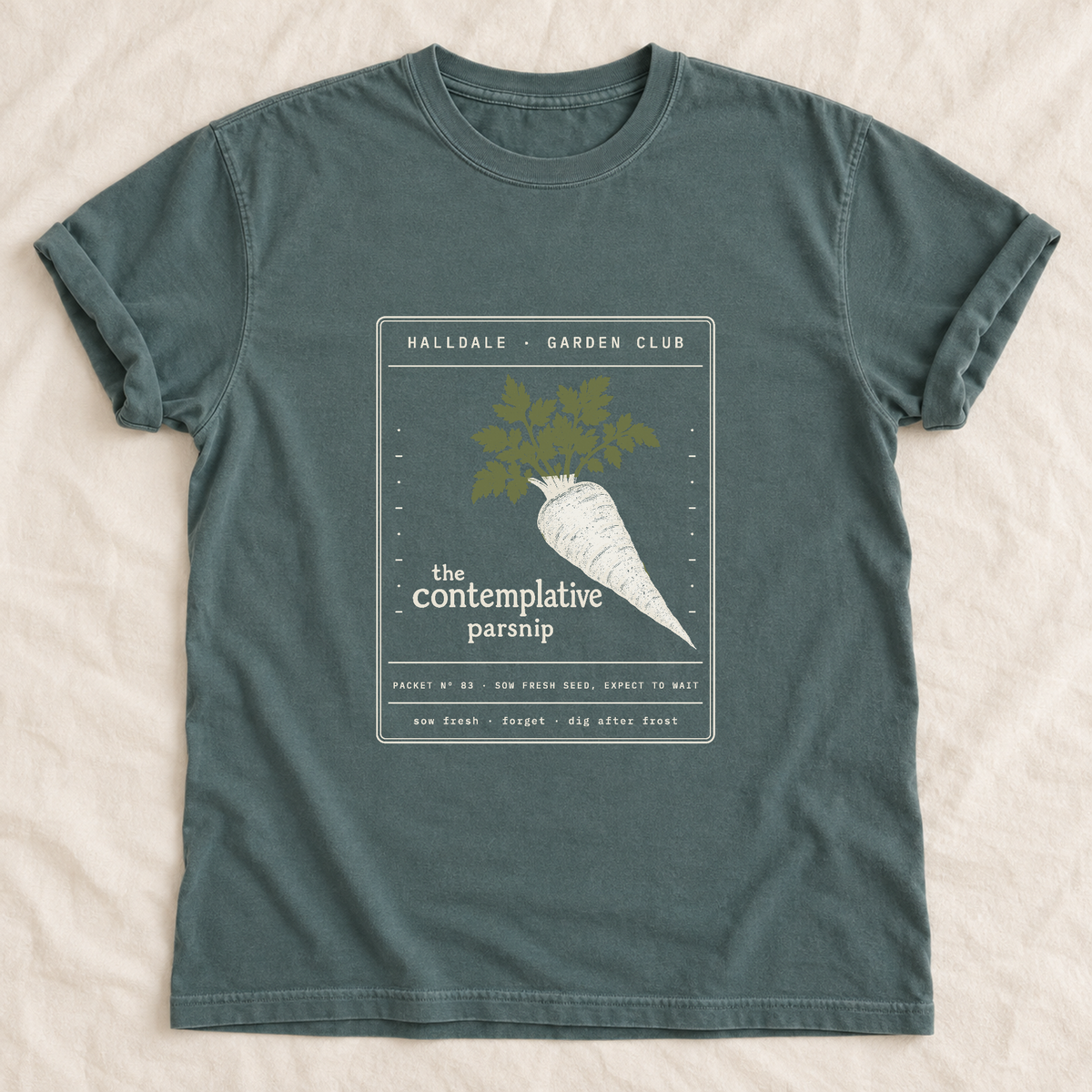 The Contemplative Parsnip tee in Blue Spruce, laid flat