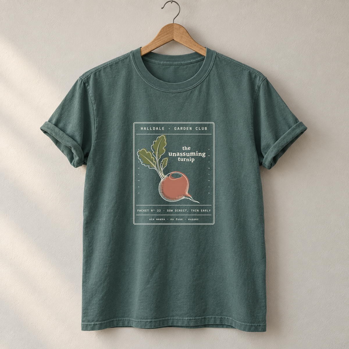The Unassuming Turnip tee in Blue Spruce, on a hanger