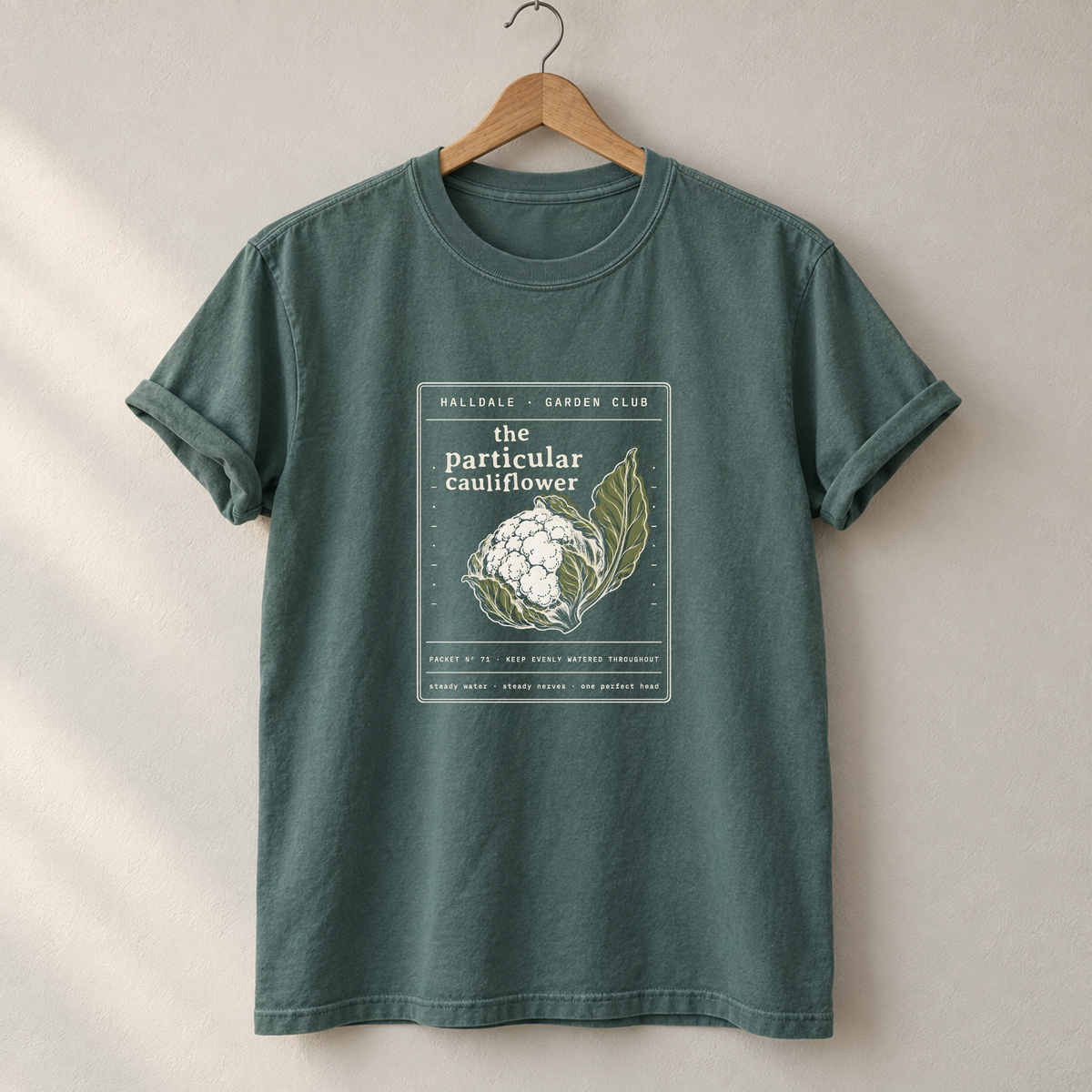 The Particular Cauliflower tee in Blue Spruce, on a hanger