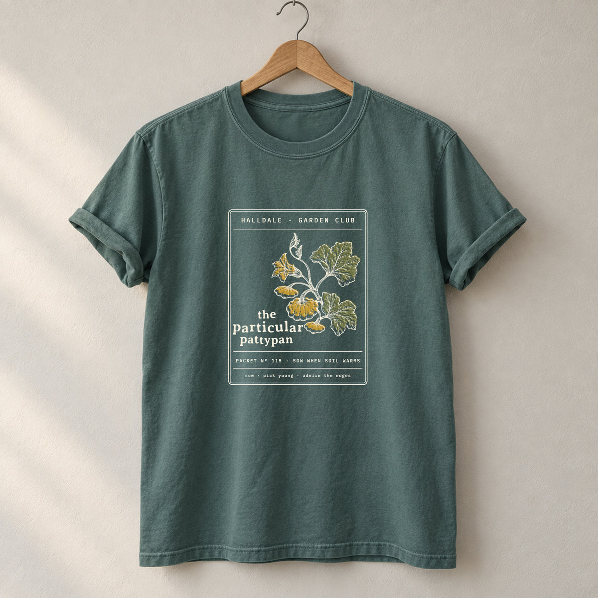 The Particular Pattypan tee in Blue Spruce, on a hanger