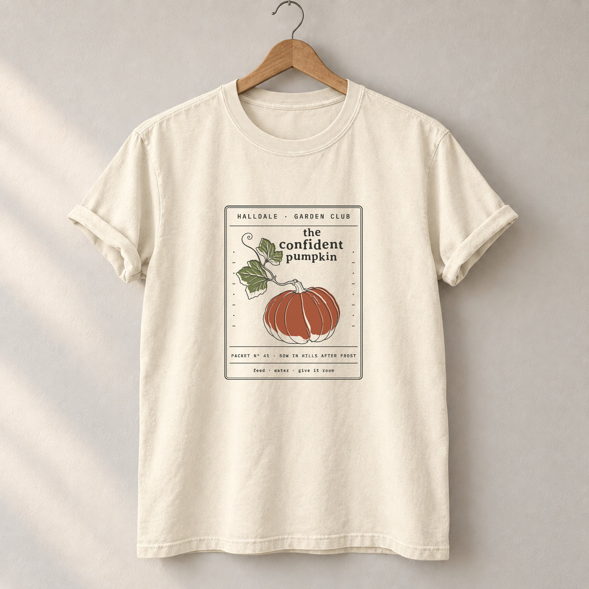 The Confident Pumpkin tee in Ivory, on a hanger