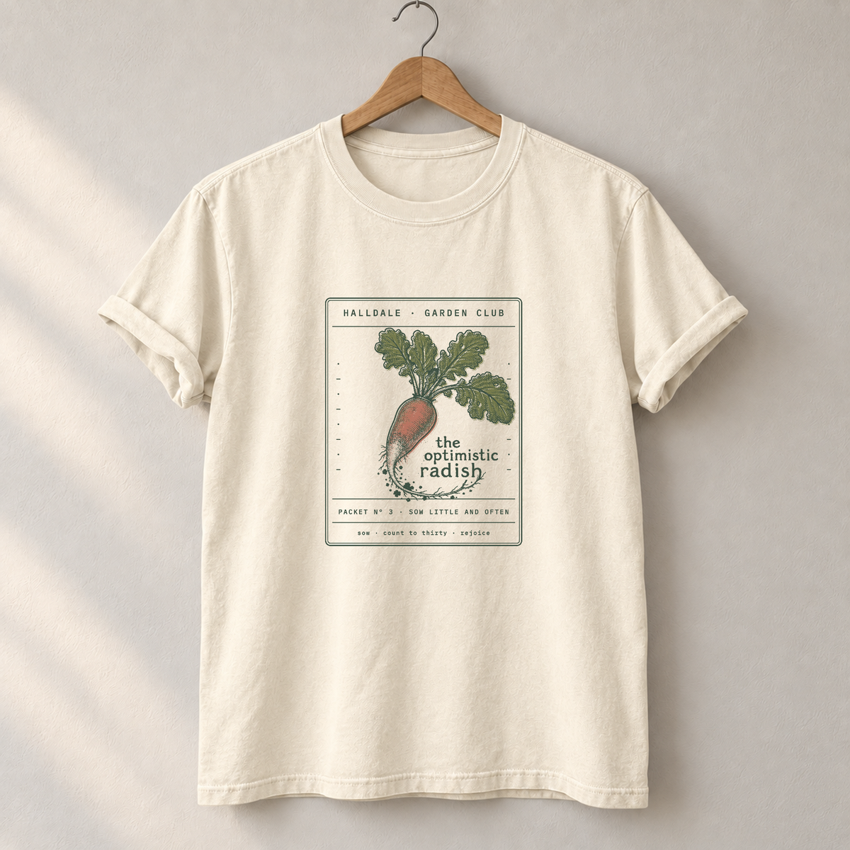The Optimistic Radish tee in Ivory, on a hanger