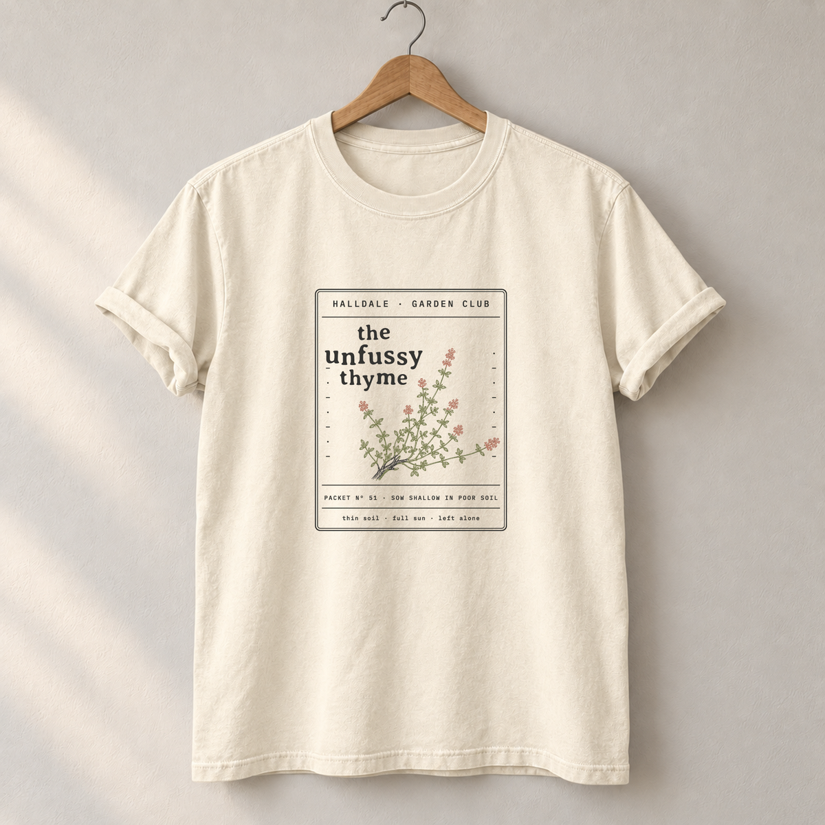 The Unfussy Thyme tee in Ivory, on a hanger