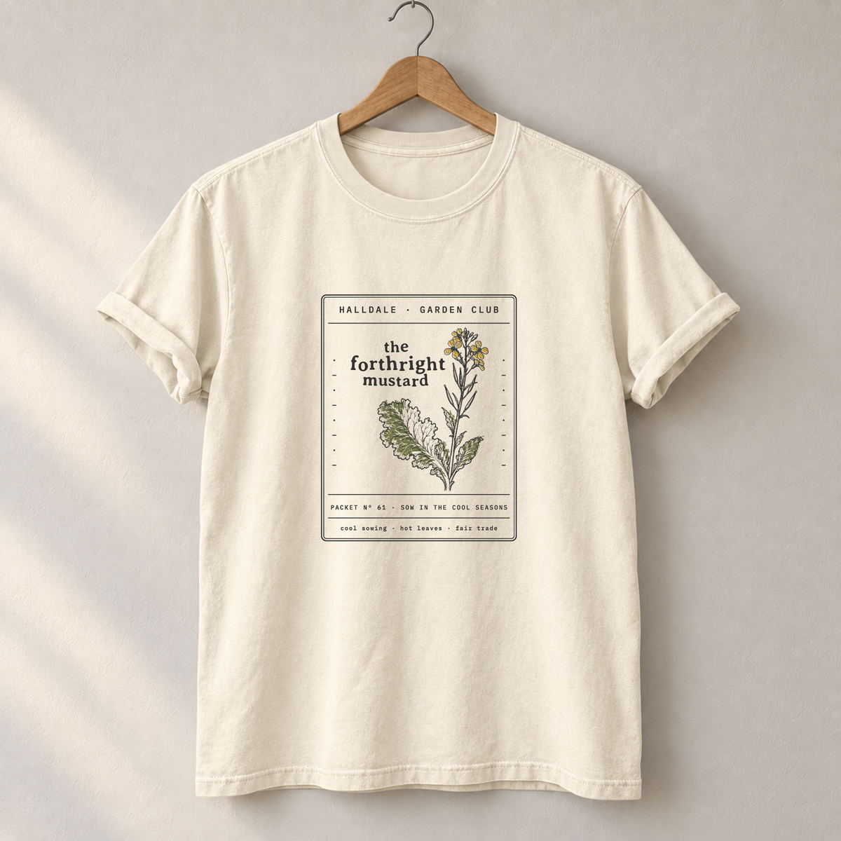 The Forthright Mustard tee in Ivory, on a hanger