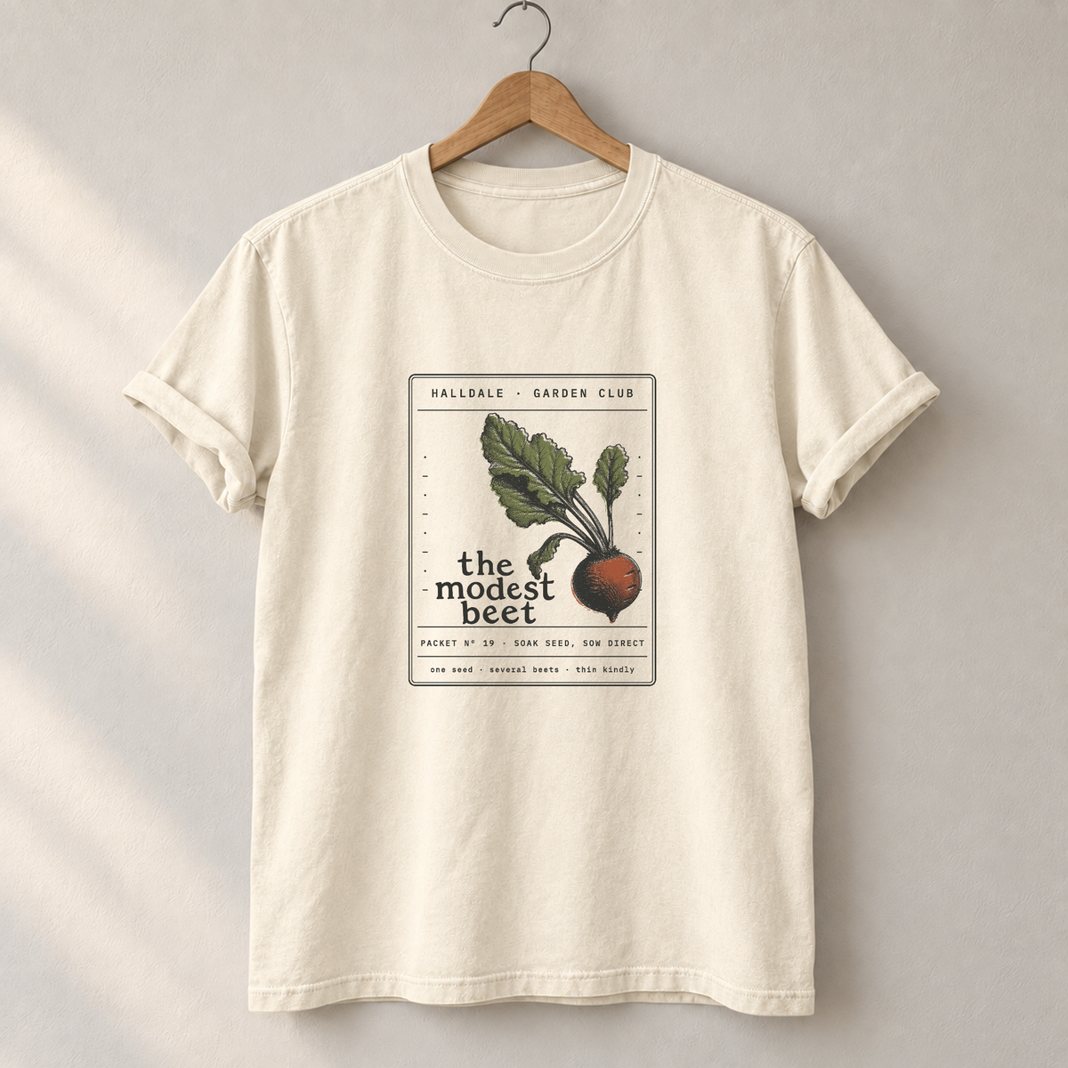 The Modest Beet tee in Ivory, on a hanger