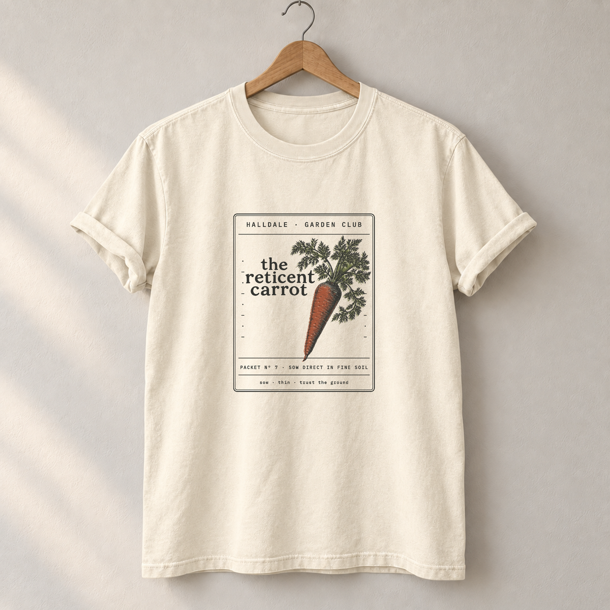 The Reticent Carrot tee in Ivory, on a hanger