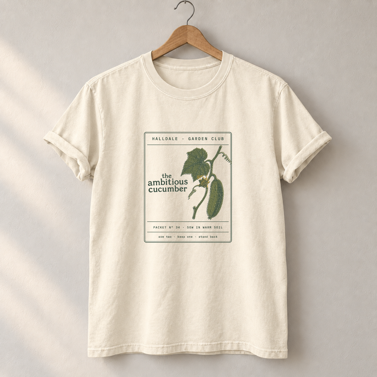 The Ambitious Cucumber tee in Ivory, on a hanger
