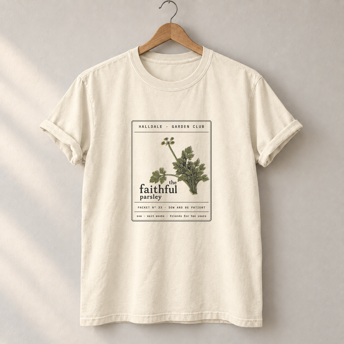 The Faithful Parsley tee in Ivory, on a hanger