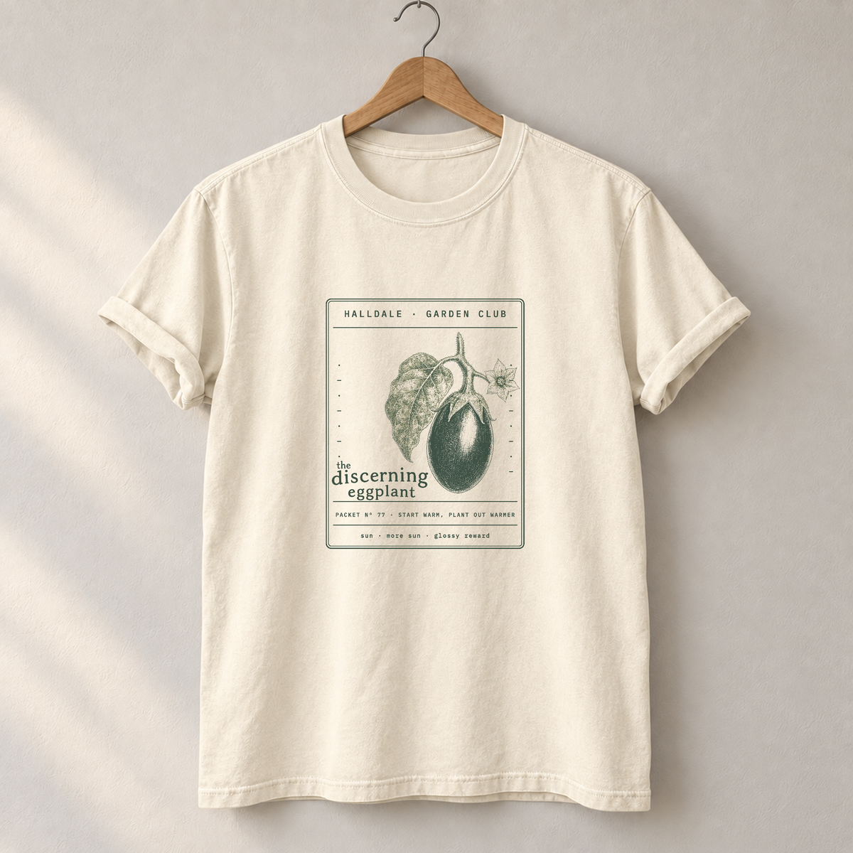 The Discerning Eggplant tee in Ivory, on a hanger