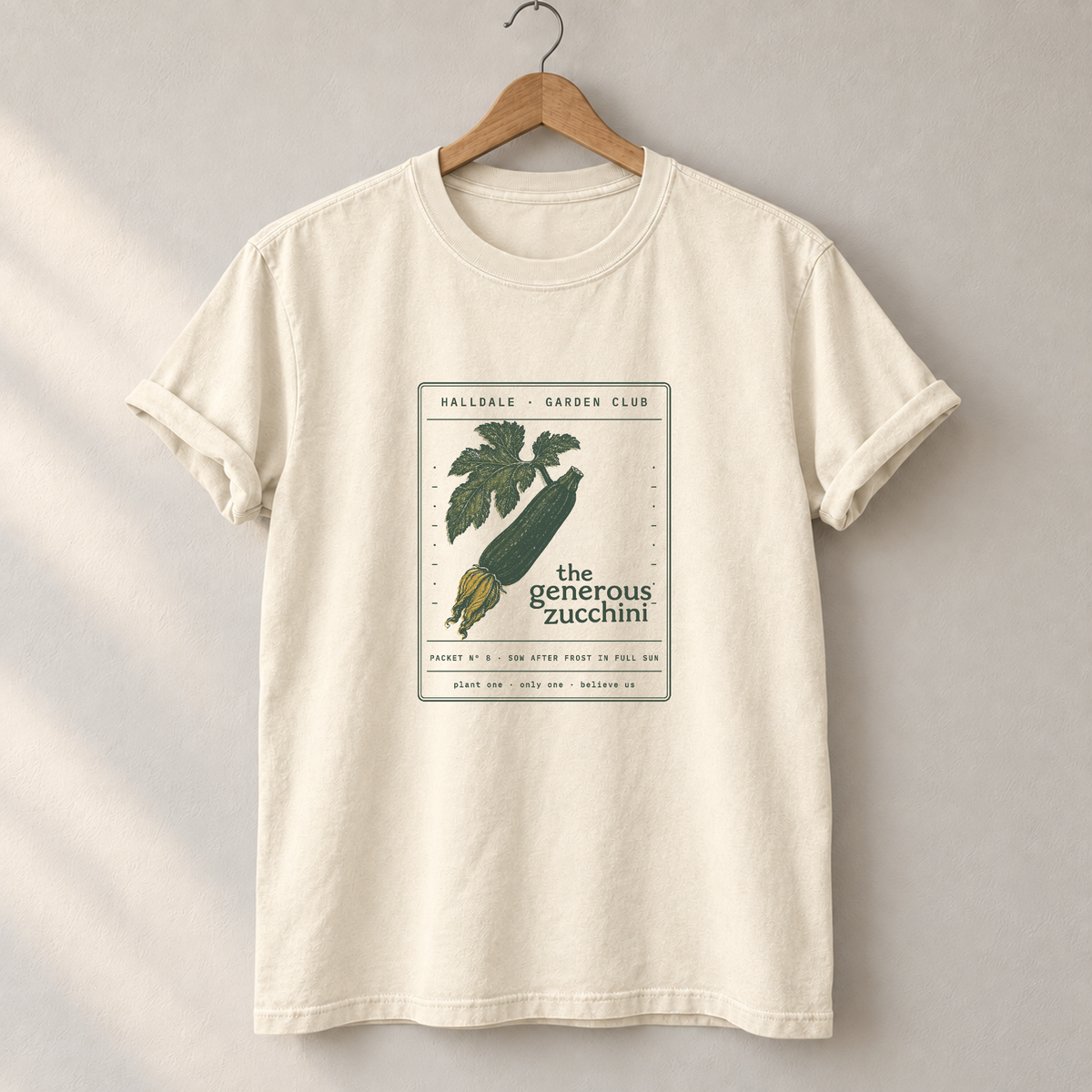The Generous Zucchini tee in Ivory, on a hanger