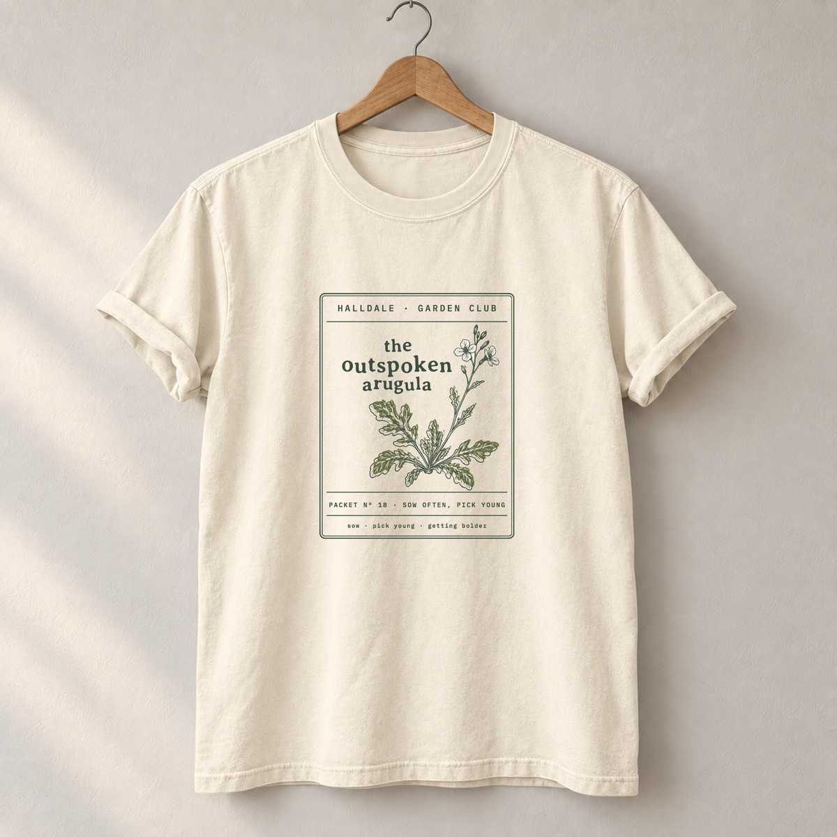 The Outspoken Arugula tee in Ivory, on a hanger